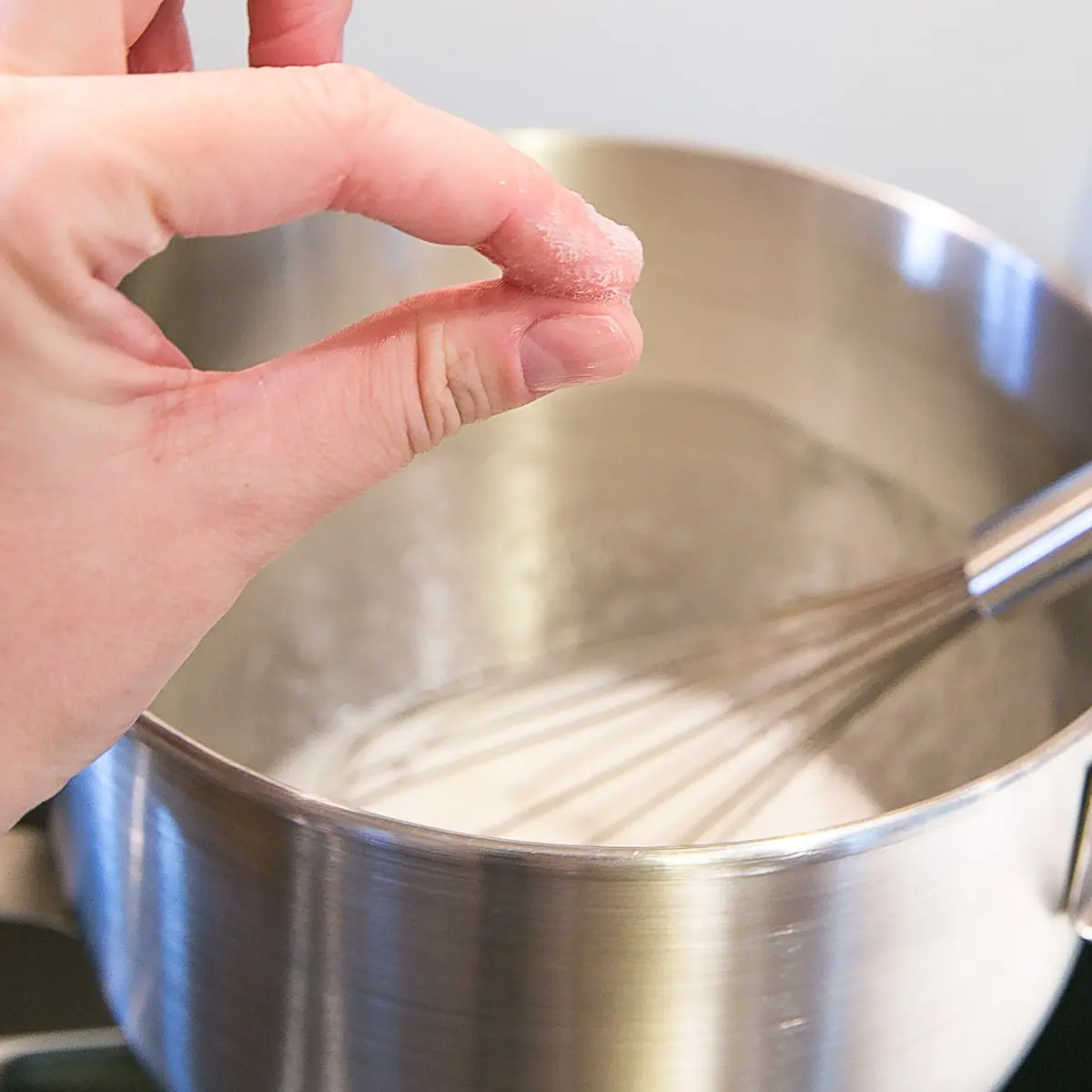 This old-fashioned 7 minute frosting recipe is light, delicious, and easy to make. A pure white frosting that's perfect for a variety of delicious desserts. | livforcake.com Testing the meringue for graininess by rubbing in between two fingers.
