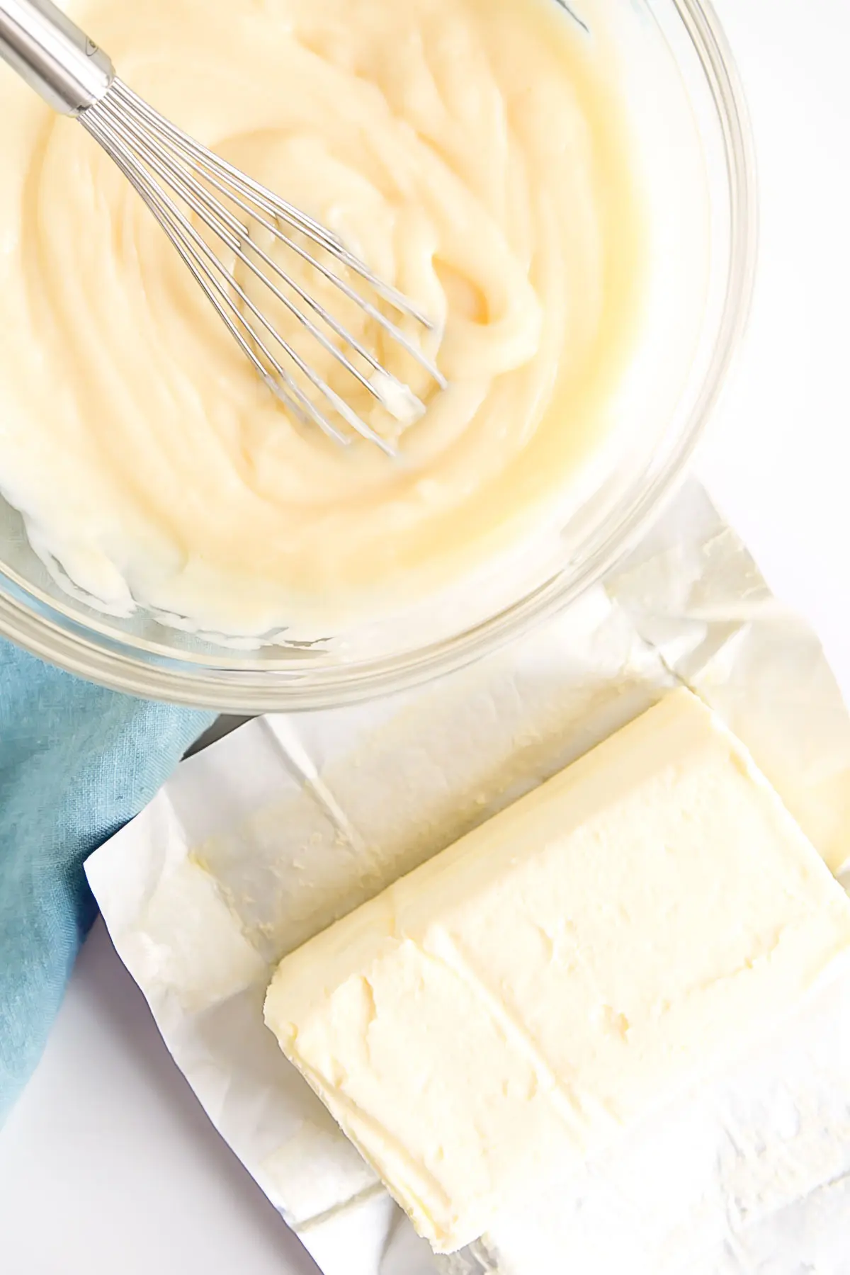 This custard-based German buttercream is made with just a few simple ingredients. Perfect for those who like a rich and silky frosting that isn't too sweet! | livforcake.com Pastry cream in a bowl with a whisk and butter next to it.