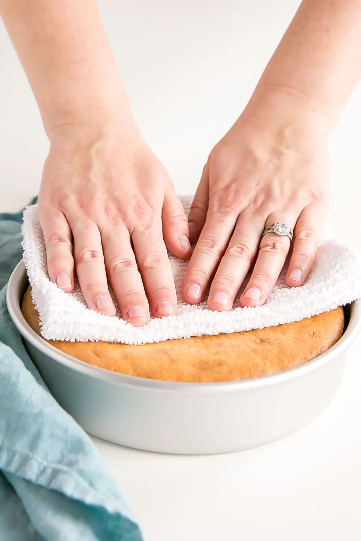 Learn how to bake flat cakes every single time! A simple tutorial on how to make sure your cakes come out nice and flat straight out of the oven. | livforcake.com Pressing down on the top of a cake gently using a tea towel.