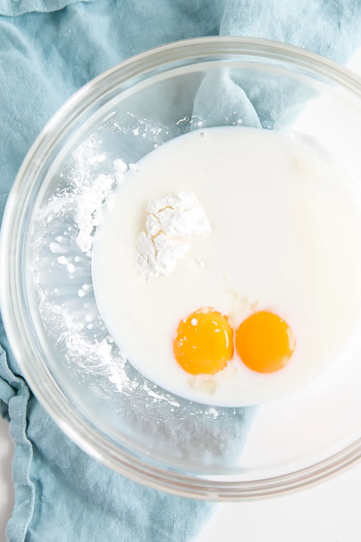 This easy Pastry Cream (Creme Patissiere) recipe is simple and delicious. A rich and creamy vanilla custard you can use in a variety of decadent desserts. | livforcake.com Eggs, cornstarch, and milk in a bowl.