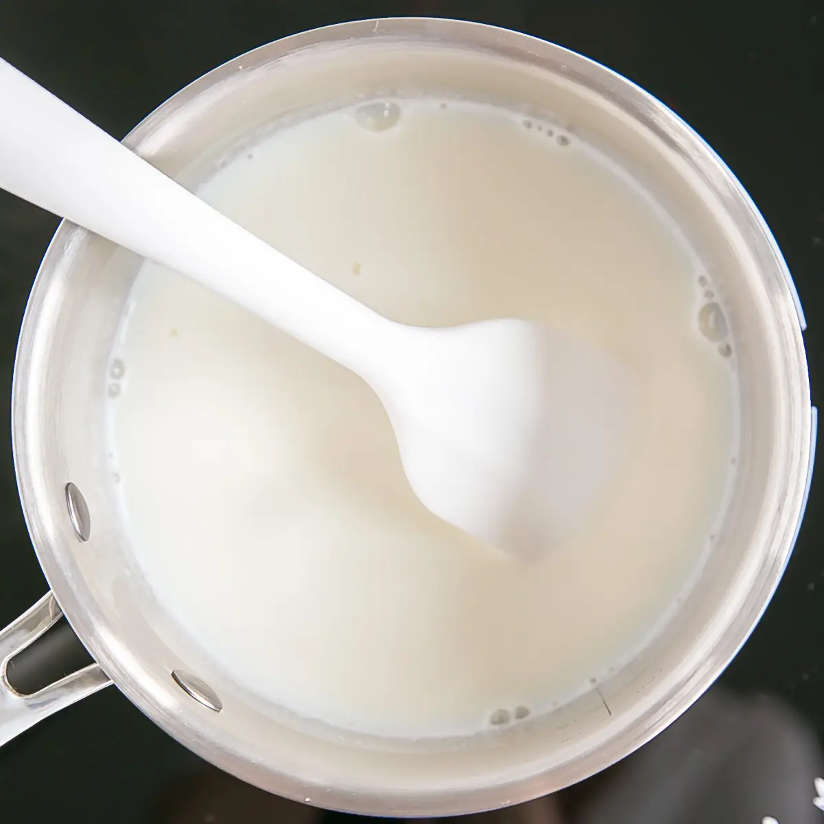 This easy Pastry Cream (Creme Patissiere) recipe is simple and delicious. A rich and creamy vanilla custard you can use in a variety of decadent desserts. | livforcake.com Milk and vanilla in a pot on the stove.