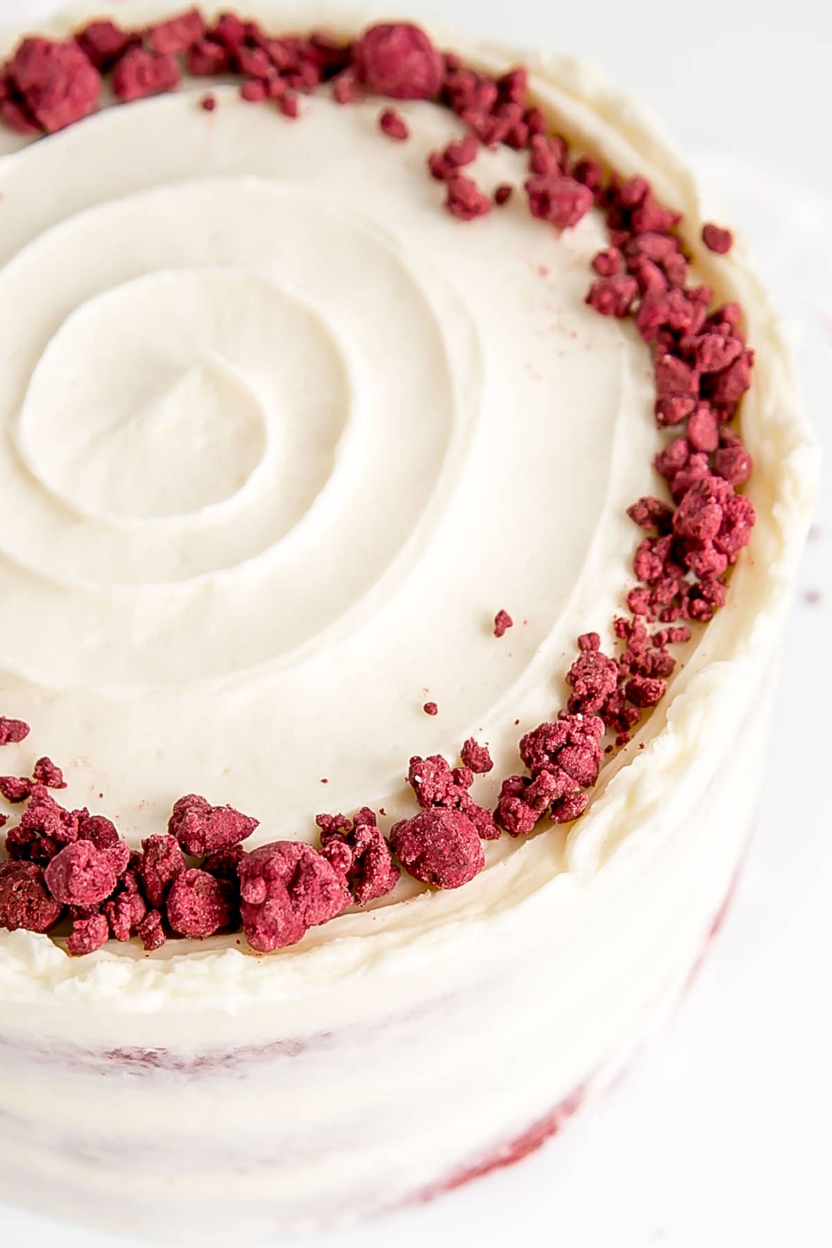 Classic Red Velvet Cake! Tender red cake layers with a hint of chocolate paired with a tangy cream cheese frosting and a red velvet crumble. | livforcake.com Angled shot of the red velvet crumble on the cake.