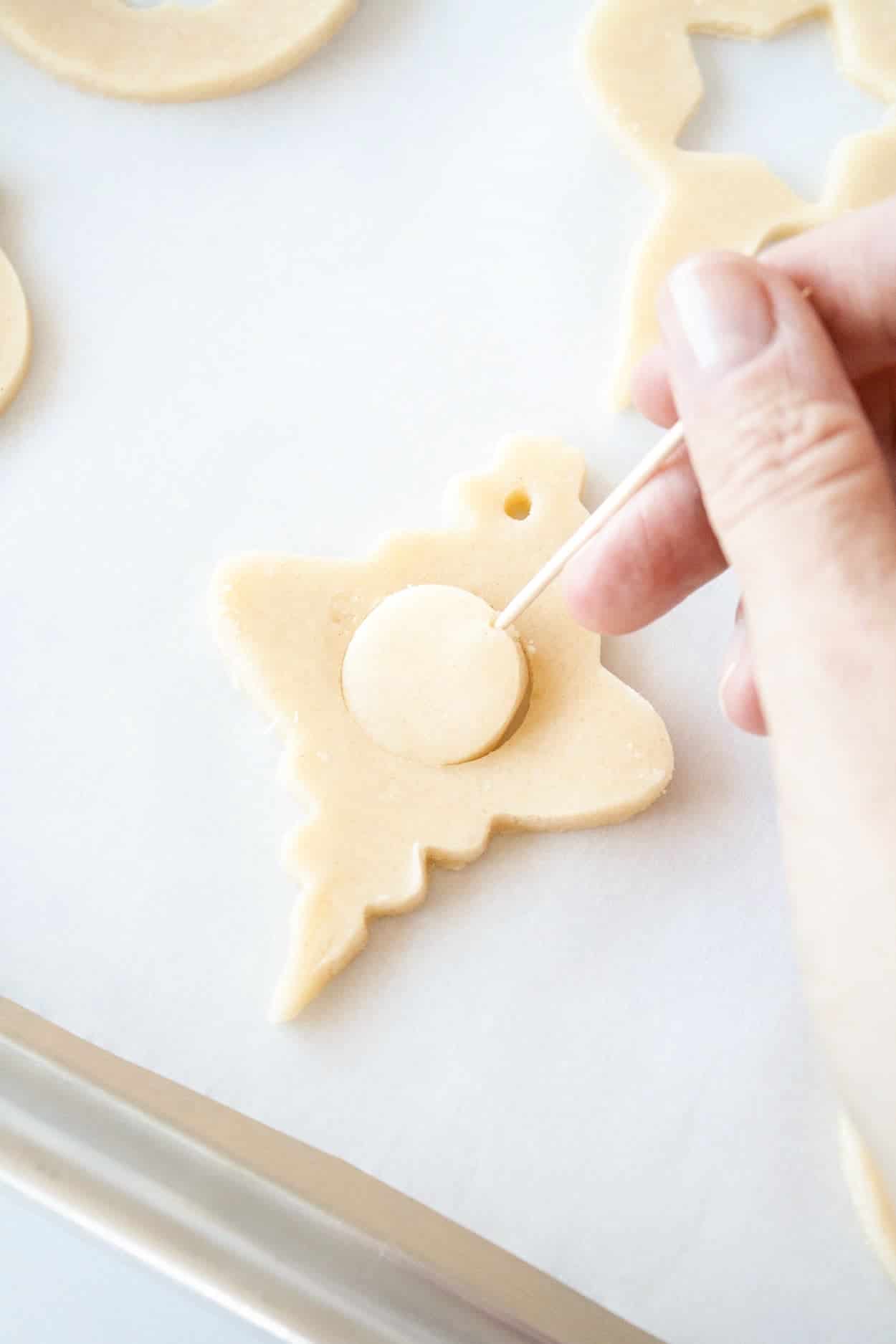 Learn how to make stunning stained glass cookies with this detailed tutorial! Perfect for holiday cookie exchanges or hanging on your tree. | livforcake.com A cookie with the cut out being removed.